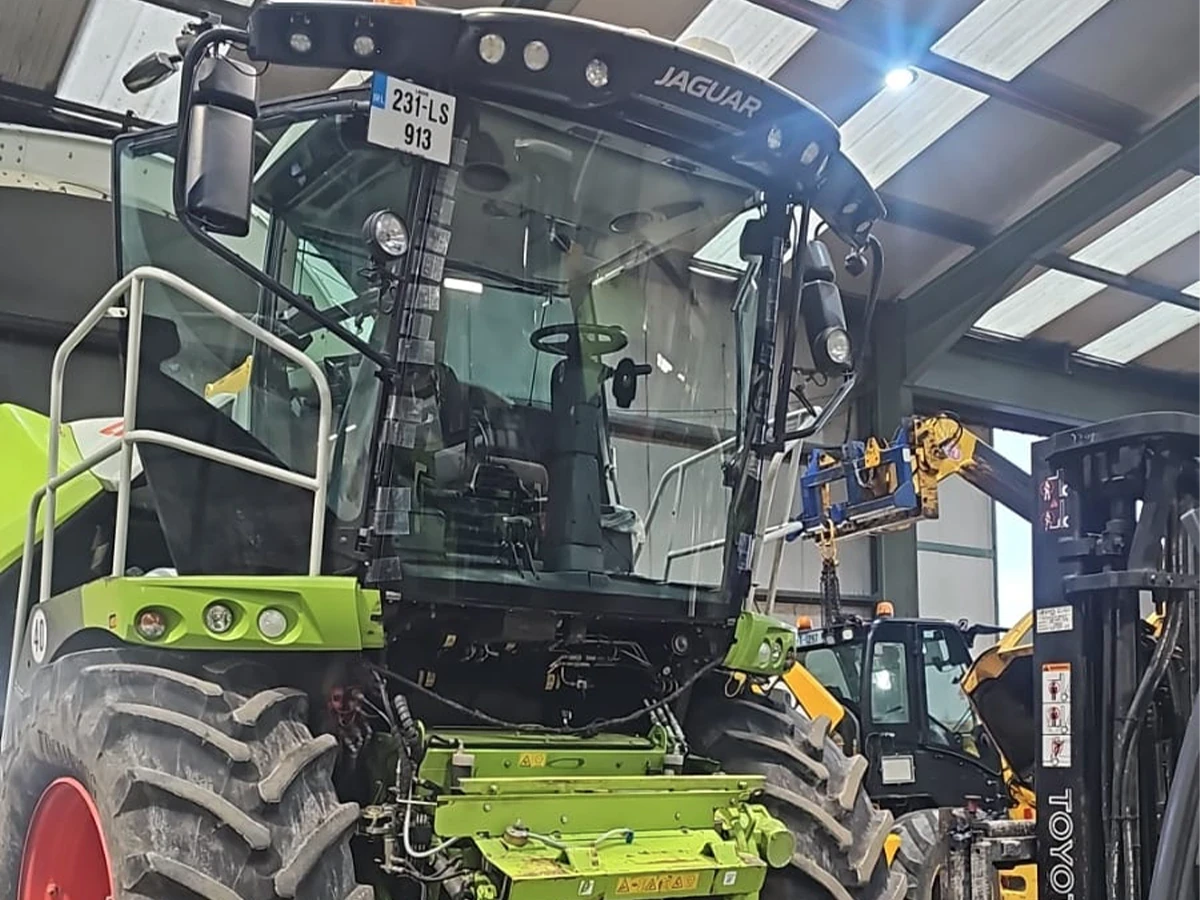 CLAAS forage harvester cab glass being replaced with a suction lifter in the workshop