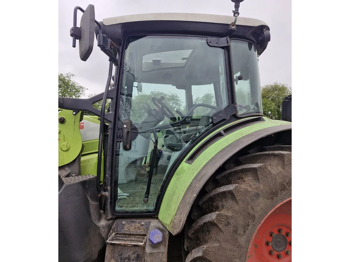 Green John Deere tractor with a newly fitted cab door glass out in the field