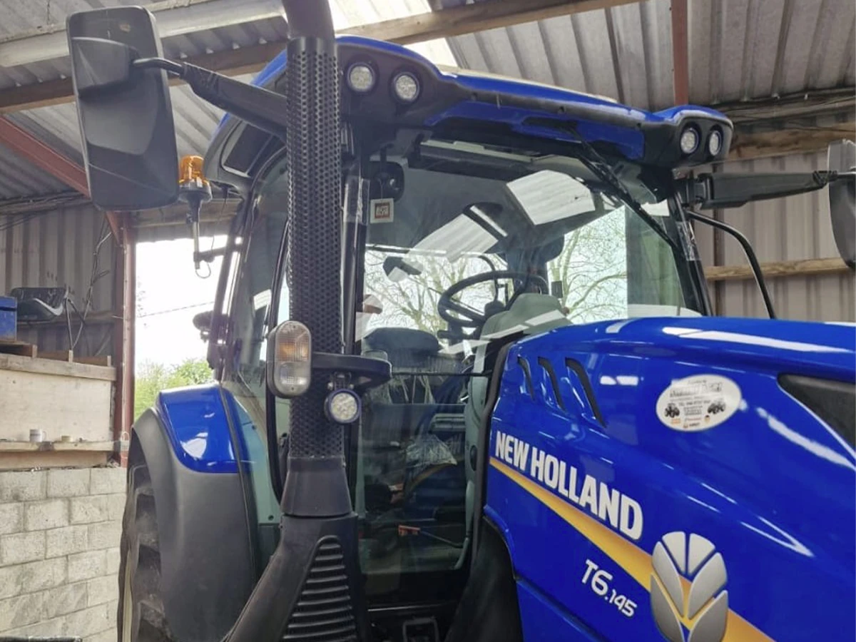 New Holland tractor cab glass replacement in a farm shed