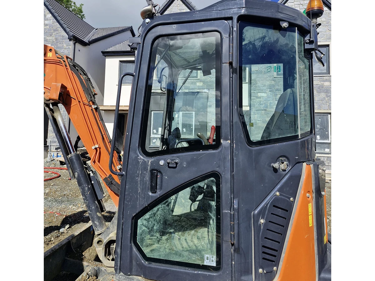 Hitachi excavator with newly fitted cab door and side glass on a housing construction site