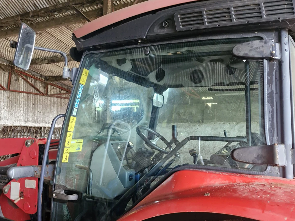 Red agricultural tractor with a newly fitted cab windscreen in a barn